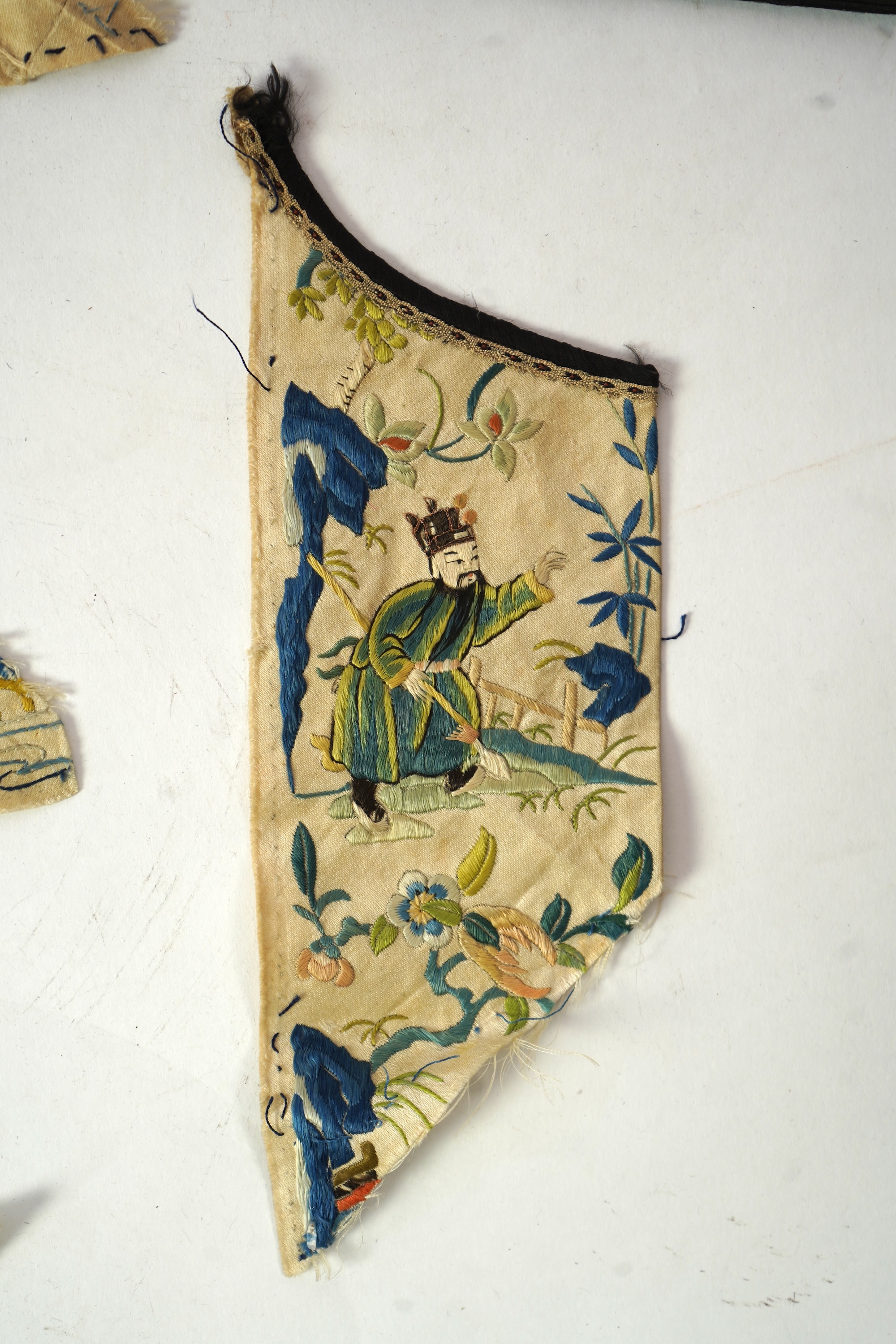A Chinese embroidered silk panel of uncut robe borders, eleven similar sleeve panels and two other items, late Qing dynasty